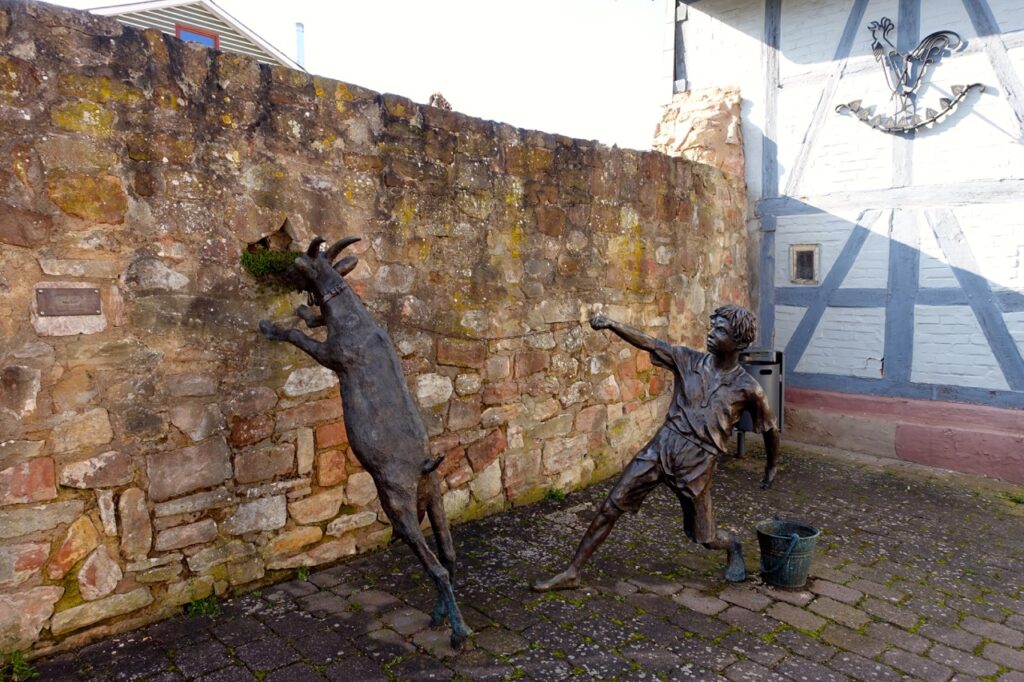Reise auf der Deutschen Maerchenstrasse, Stopp in Rotenburg an der Fulda, Statue mit Junge und Ziege, die durch eine Mauer schaut
