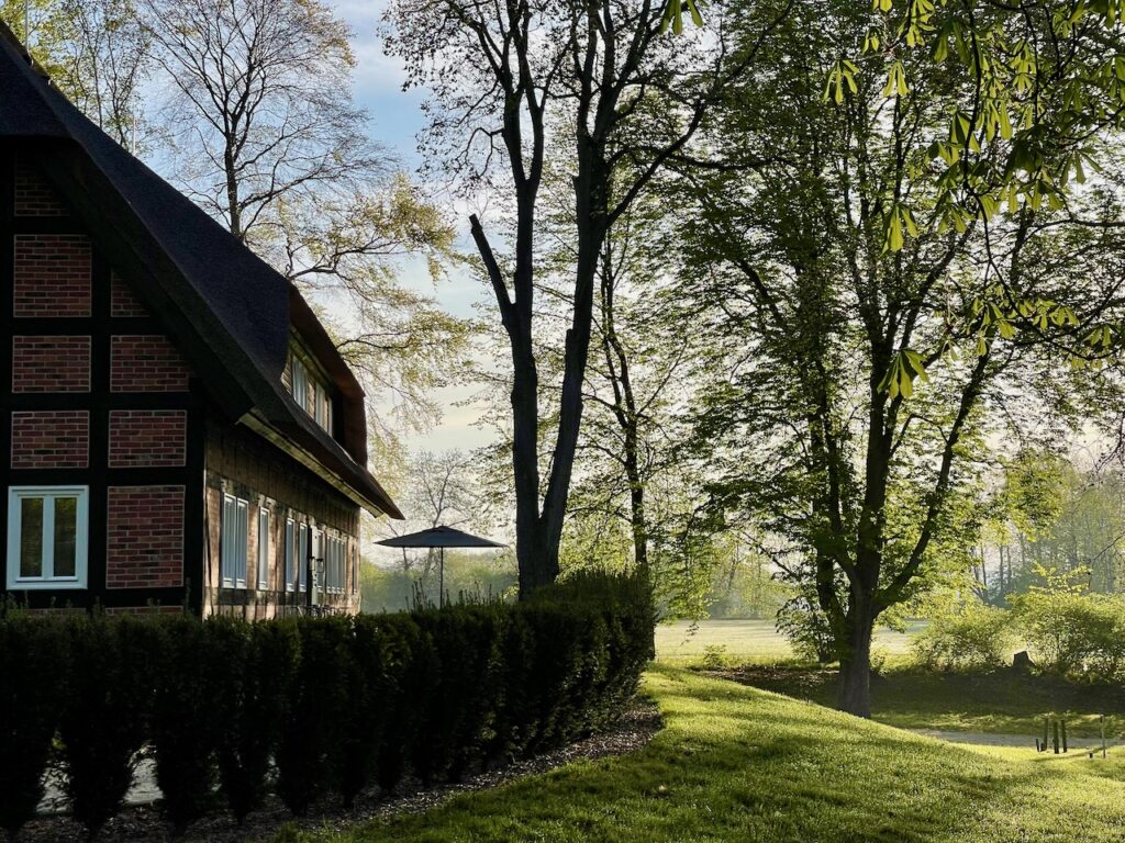 Ayurveda-Kur im Park am See an der Mecklenburgischen Seenplatte zum Sonnenaufgang, Ausschnitt Fachwerkhaus im Hotelpark