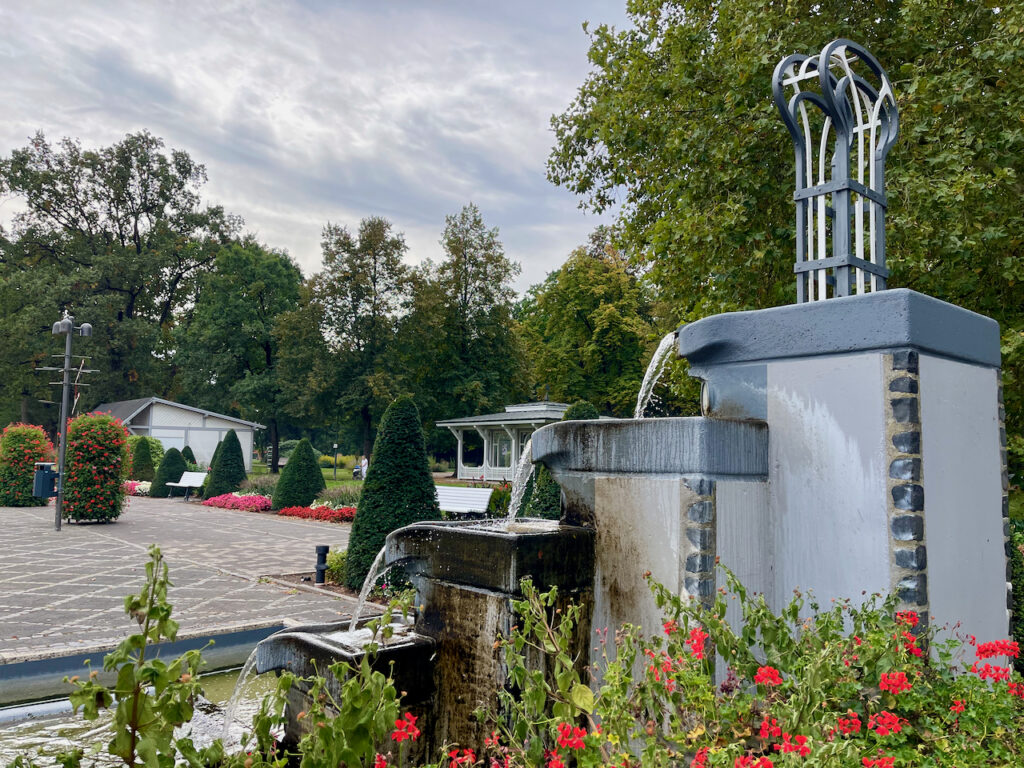 Blick vom Brunnen im Kurpark von Bad Waldliesborn, im Hintergrund ist das Pumpenhaus und Walibos Gute Stube zu sehen