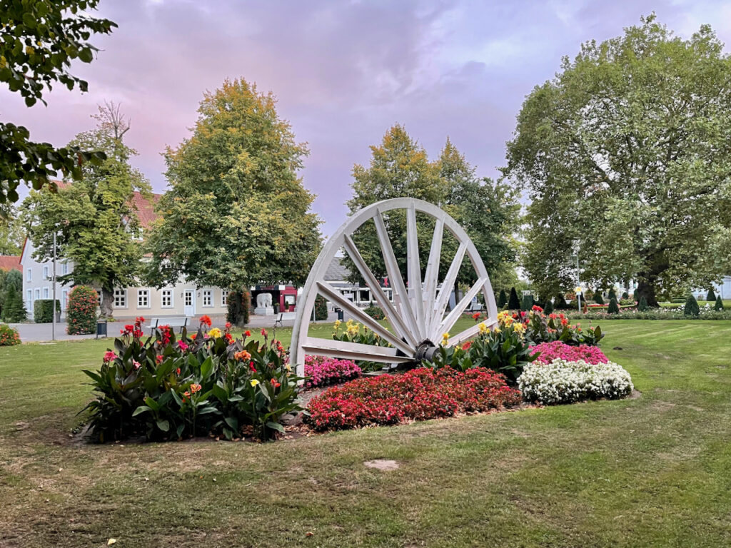 Seilscheibe im Kurpark von Bad Waldliesborn zum Sonnenuntergang, der Himmel ist leicht lila im Vordergrund bluehen Blumen