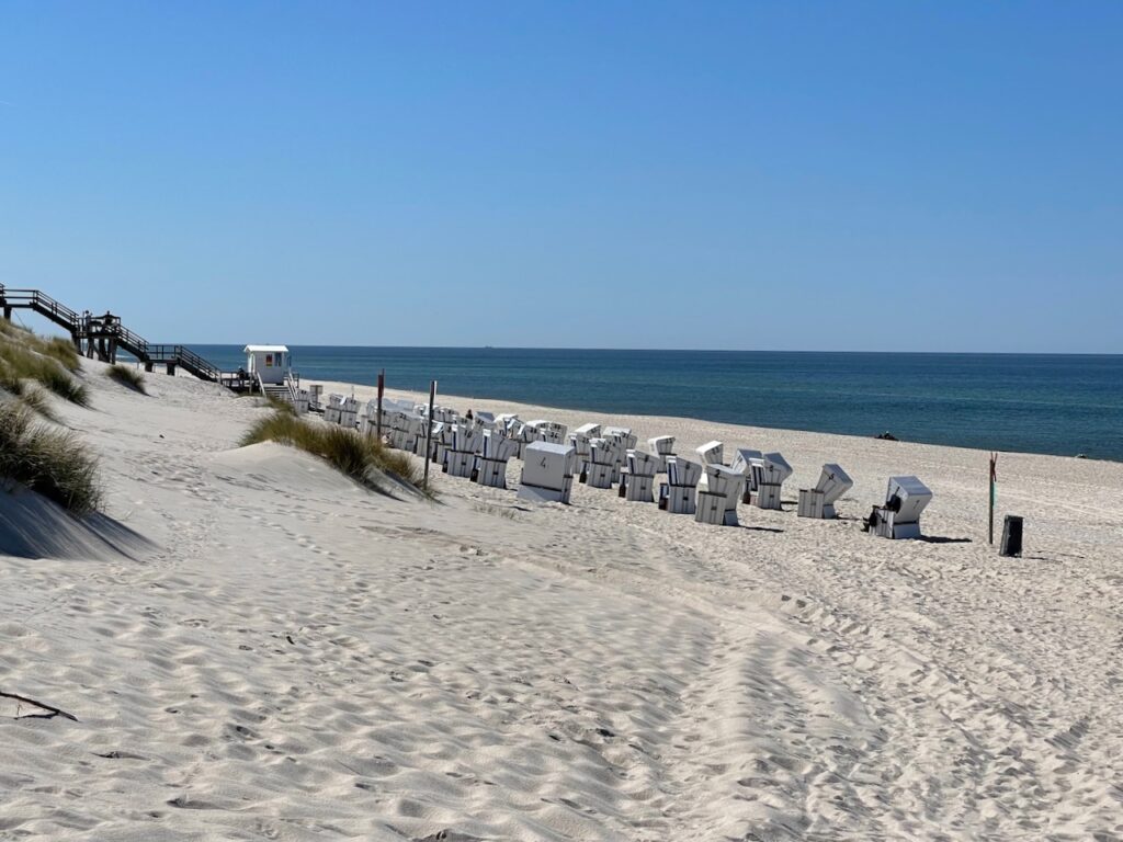 Weite und Ruhe am Strand auf Sylt - langer Strand mit Strandkoerben und das Meer im Hintergrund