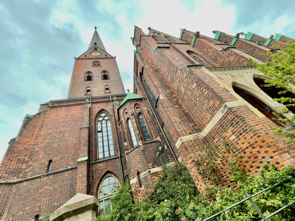 Hamburg bei Regen auf den Turm der St. Petri Kirche steigen und den Blick ueber Hamburg geniessen. Bild zeigt Blick an der Kirche hoch zum Turm vom Fussweg.