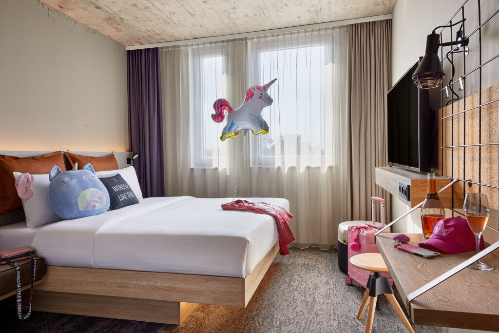 Blick in ein Zimmer im Moxy Hotel, bunt, mit einem Einhorn-Luftballon ueber dem Bett